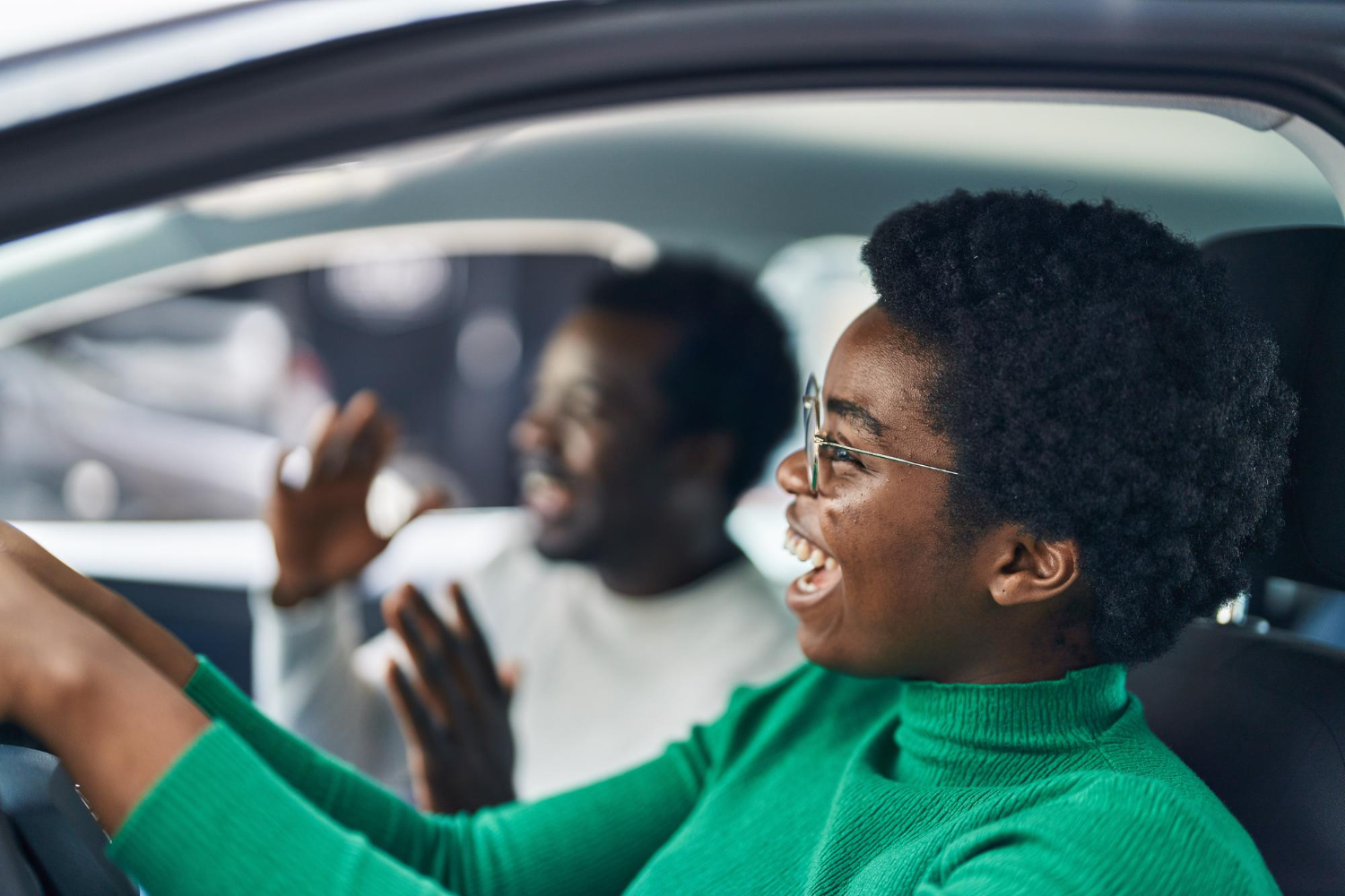 A learner laughing at the wheel during a driving lesson with her instructor